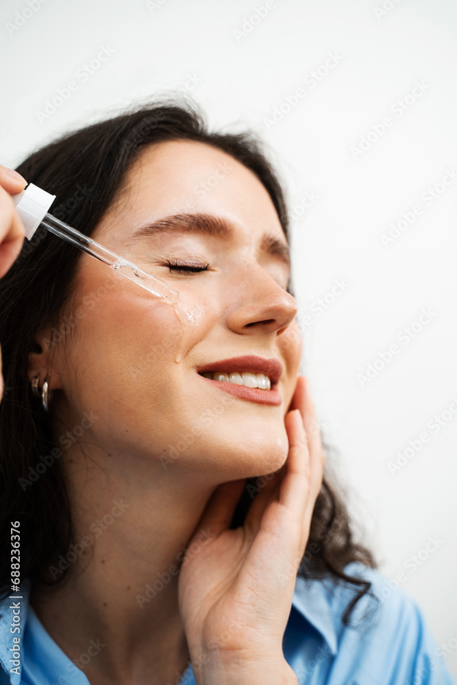 Attractive girl drops essential oil on facial skin close-up. Young woman is applying moisturizing serum on her face. Attractive girl drops essential oil on facial skin close-up. Young woman is applying moisturizing serum on her face.