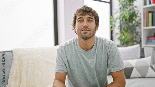 Young man sitting on sofa with serious expression at home