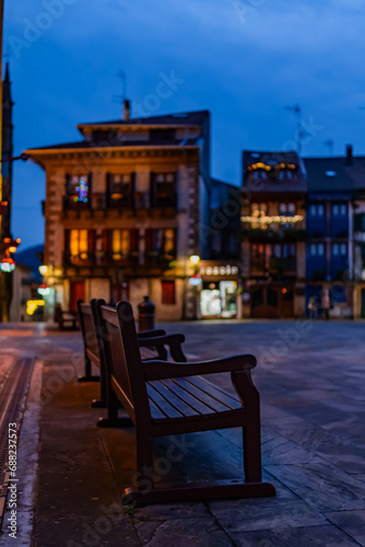Solitary bench adorned for Christmas  urban bokeh  winter ambiance in Hondarribia square.