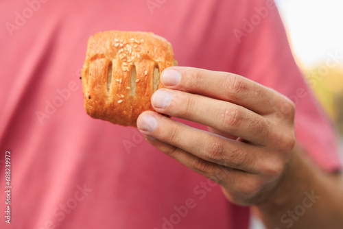 A guy's hand holds a mini puff pastry with cheese, snack and fast food concept. Selective focus on hands