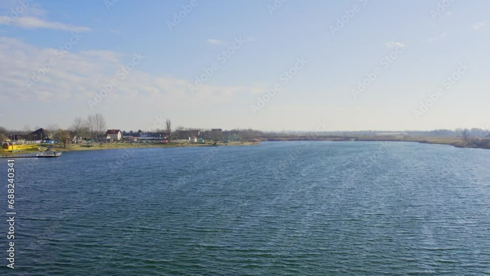 Drone flies above water surface of beautiful blue lake under blue sky in Zrenjanin Drone flies above water surface of beautiful blue lake under blue sky in Zrenjanin