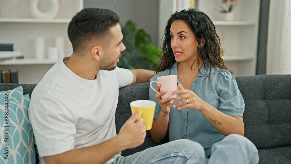 Man and woman couple sitting on sofa drinking coffee at home