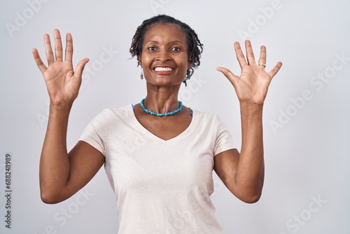 African woman with dreadlocks standing over white background showing and pointing up with fingers number ten while smiling confident and happy.