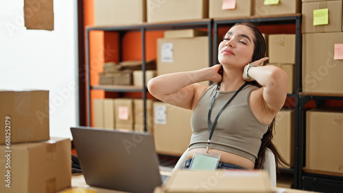 Young beautiful hispanic woman ecommerce business worker combing hair with hands at office photo