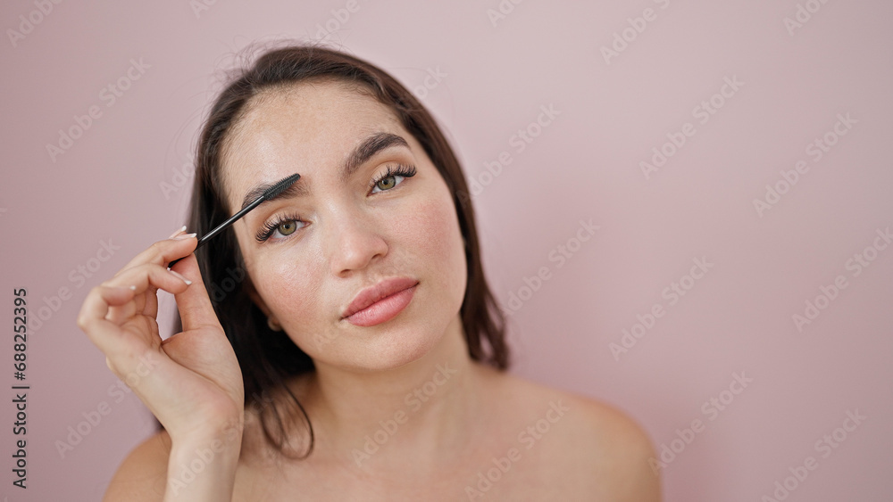 Young beautiful hispanic woman applying make up on eyelashes over isolated pink background Young beautiful hispanic woman applying make up on eyelashes over isolated pink background
