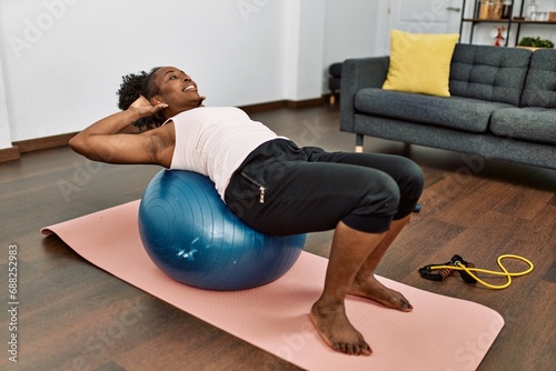 African american woman training abs exercise using fit ball at home
