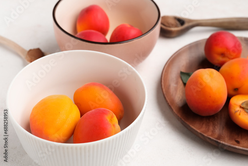 Bowls and plate with sweet apricots on white background