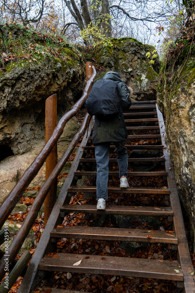 Hiker ascends fall stairs, hooded silhouette.