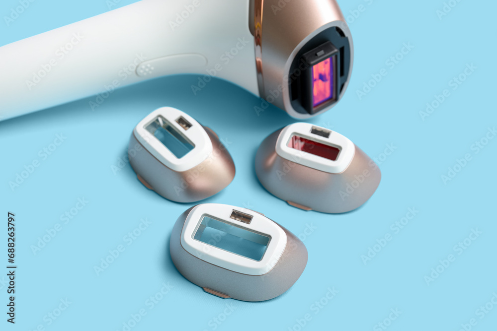 Modern photoepilator with attachments on blue background Modern photoepilator with attachments on blue background