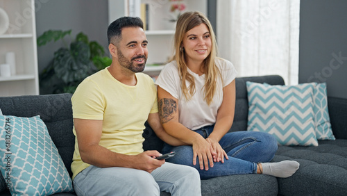 Man and woman couple sitting on sofa watching television at home