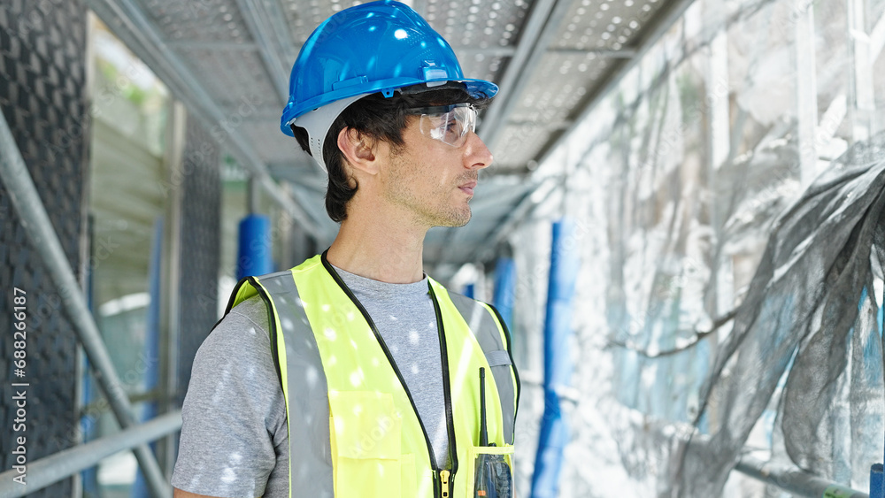 Young hispanic man architect wearing hardhat standing with serious face at construction place Young hispanic man architect wearing hardhat standing with serious face at construction place