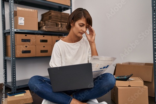 Young beautiful hispanic woman ecommerce business worker reading document with serius expression at office photo