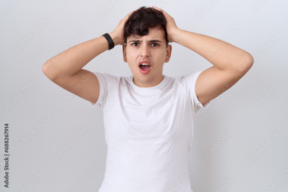 Young non binary man wearing casual white t shirt crazy and scared with hands on head, afraid and surprised of shock with open mouth Young non binary man wearing casual white t shirt crazy and scared with hands on head, afraid and surprised of shock with open mouth