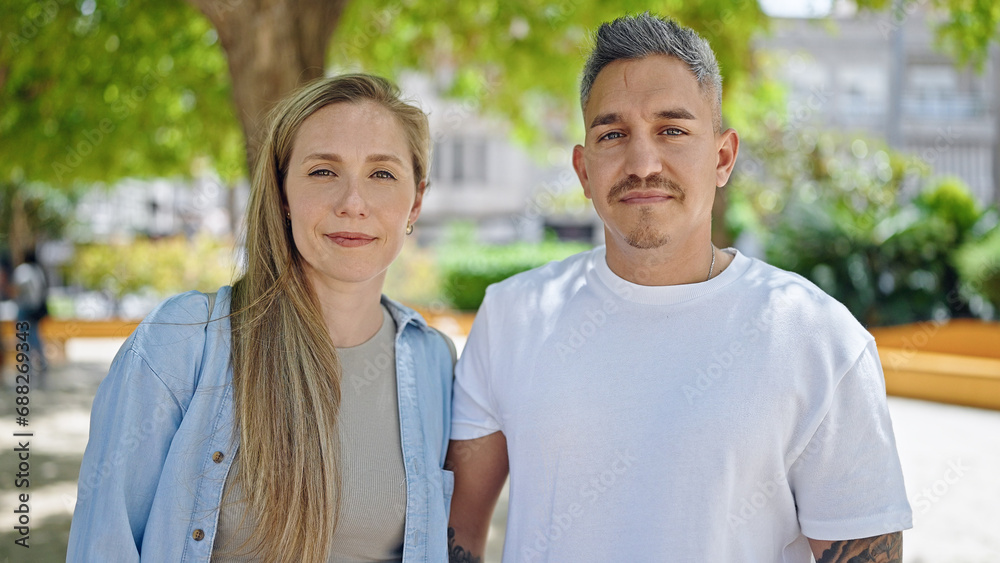 Man and woman couple standing together with serious face at park Man and woman couple standing together with serious face at park