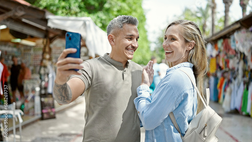 Man and woman couple smiling confident having video call at street market