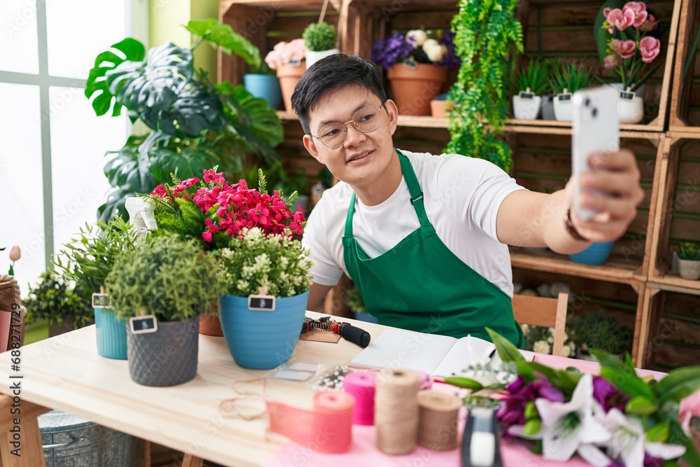 Young chinese man florist make selfie by smartphone at flower shop