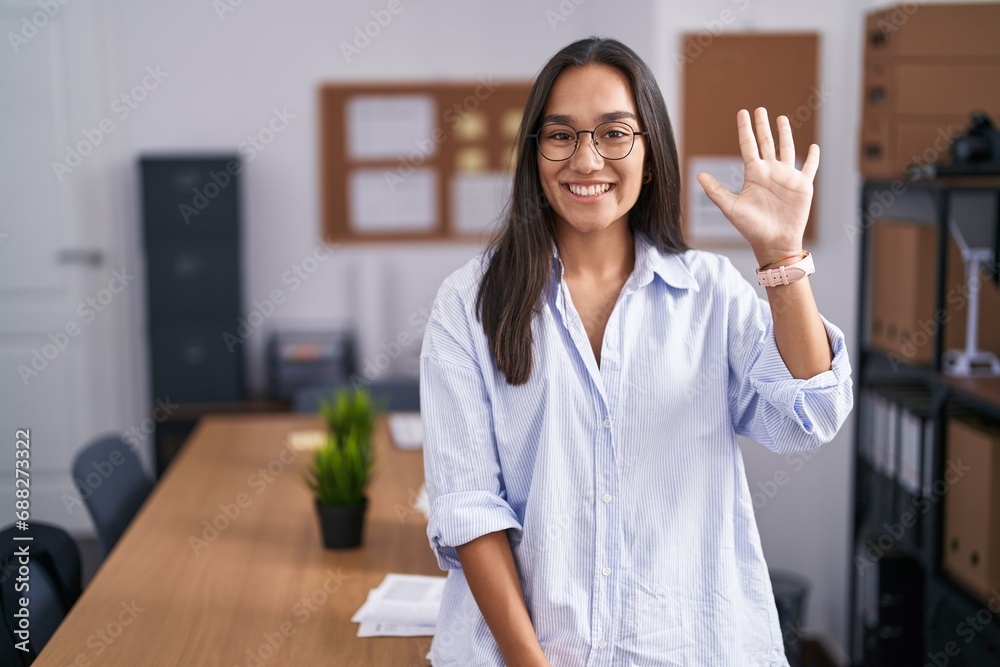 Young hispanic woman at the office showing and pointing up with fingers number five while smiling confident and happy. Young hispanic woman at the office showing and pointing up with fingers number five while smiling confident and happy.