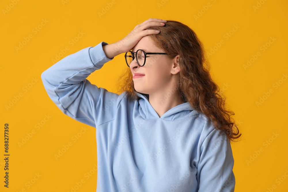 Portrait of worried young woman covering face with hand on yellow background Portrait of worried young woman covering face with hand on yellow background