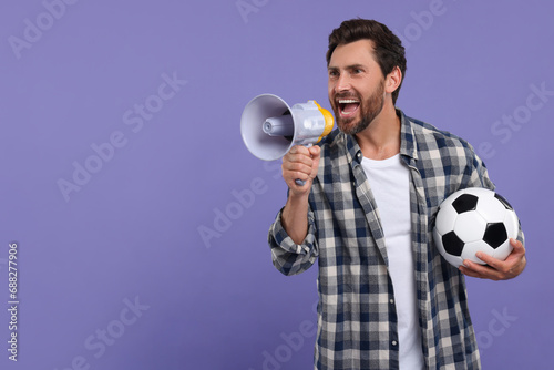 Emotional sports fan with soccer ball and megaphone on purple background, space for text
