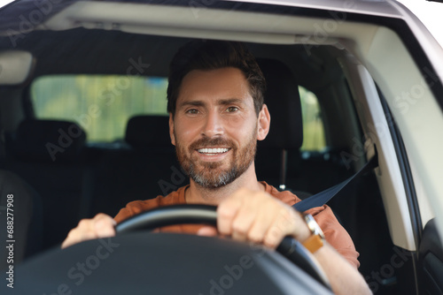 Enjoying trip. Happy bearded man driving car, view through windshield
