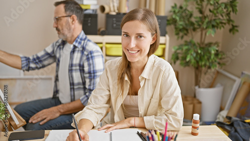 Two smiling artists confidently enjoy drawing together on canvas and paper at their cozy art studio - a joyful couple's hobby and education in painting