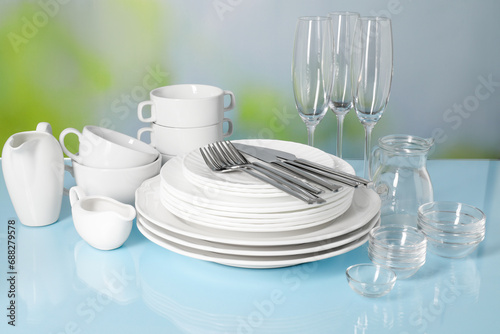 Set of clean dishes, glasses and cutlery on light blue table