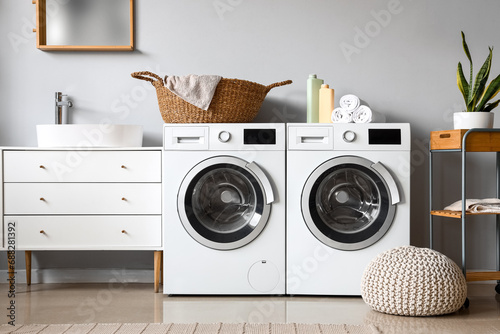 Interior of laundry room with washing machines  wicker basket and cleaning supplies