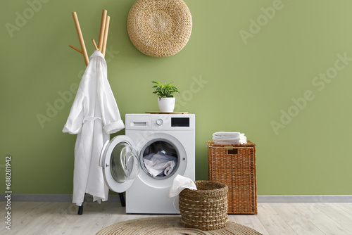 Laundry room interior with washing machine, wicker basket and bathrobe on rack photo
