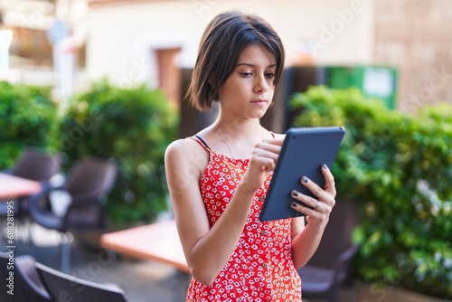 Adorable hispanic girl using touchpad with serious expression at street photo