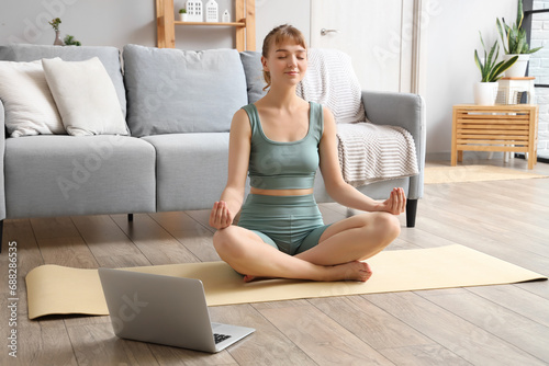 Sporty young woman meditating at home