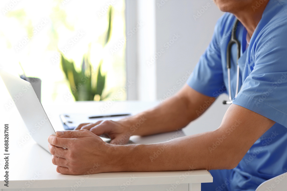 Mature doctor working with laptop at desk in medical office, closeup Mature doctor working with laptop at desk in medical office, closeup