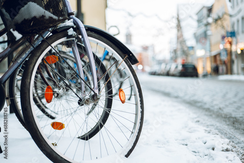 Winter in the city. Bicycle wheels in snow on blurred city background.Snowy winter weather.Bicycle traffic in winter. Traffic in winter season 