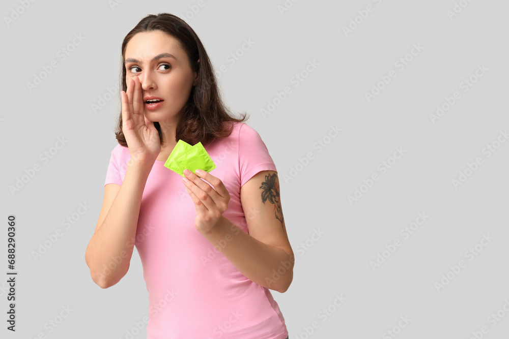 Beautiful young woman with condoms on grey background. Safe sex concept Beautiful young woman with condoms on grey background. Safe sex concept