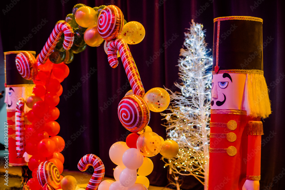 Naklejka premium Christmas decorations such as giant nutcracker dolls, balloons of different shapes such as candy, stars and classic balloons, in the background a Christmas tree.