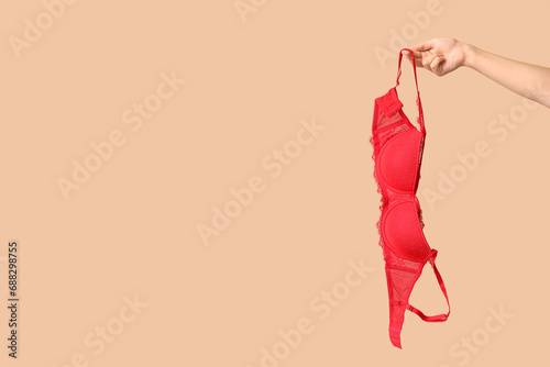 Female hand with sexy red bra on color background