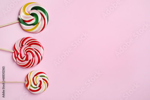 Sticks with different colorful lollipops on pink background  flat lay. Space for text