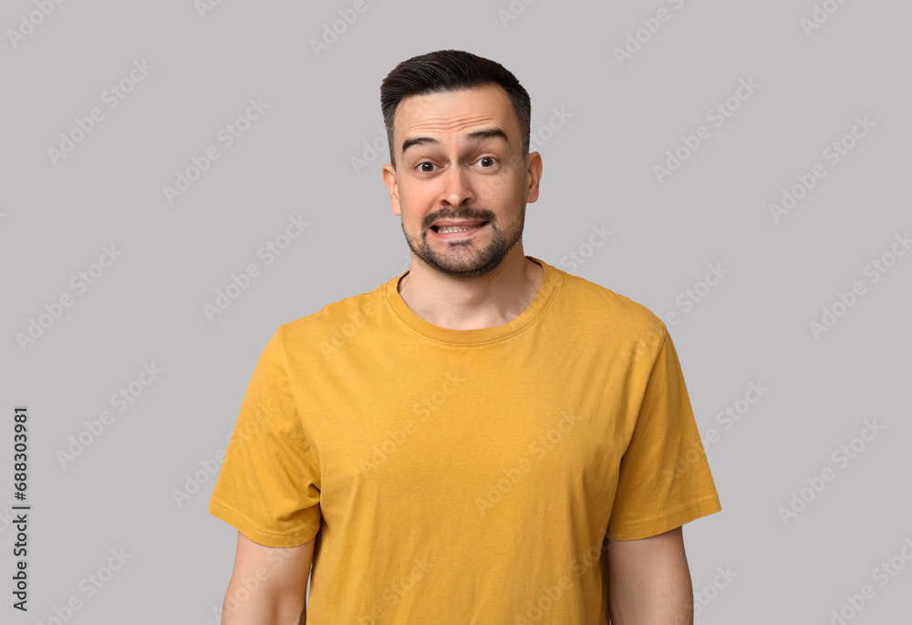 Handsome worried young man on grey background