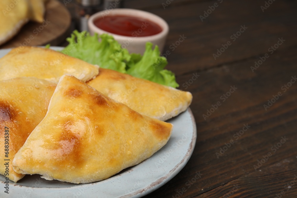 Delicious samosas and lettuce on wooden table, closeup. Space for text