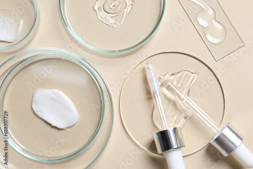 Pipettes, cosmetic serum and petri dishes with samples on beige background, flat lay