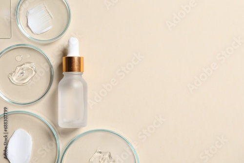 Bottle of cosmetic serum and petri dishes with samples on beige background, flat lay. Space for text photo