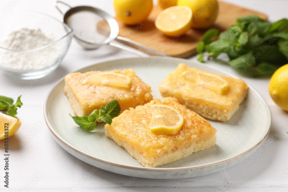 Tasty lemon bars and mint on white table, closeup Tasty lemon bars and mint on white table, closeup