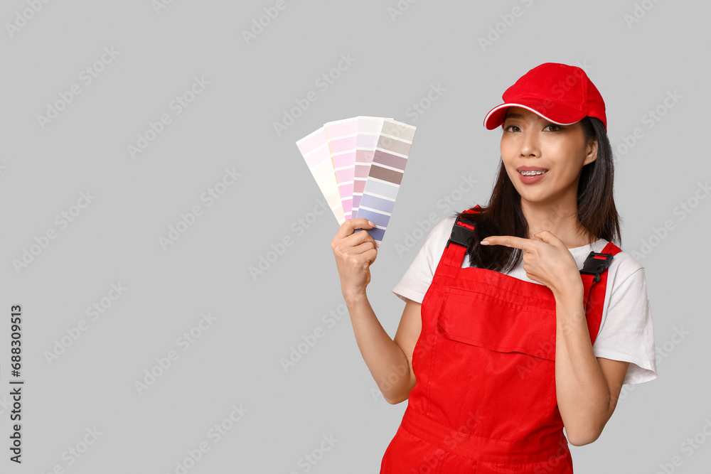 Female Asian painter pointing at paint color palettes on grey background Female Asian painter pointing at paint color palettes on grey background