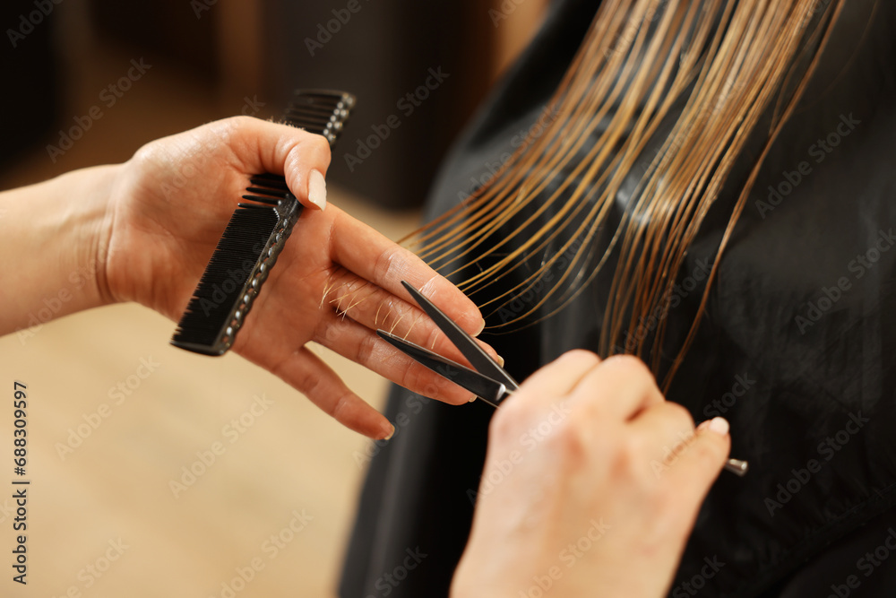 Professional hairdresser cutting girl's hair in beauty salon, closeup