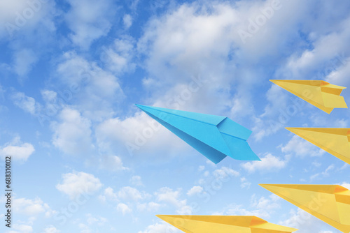 Light blue and yellow paper planes flying in sky with clouds