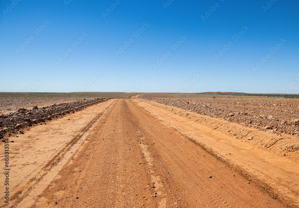 A dirt road stretching off into the distance on a Gibber plain in South Australia.