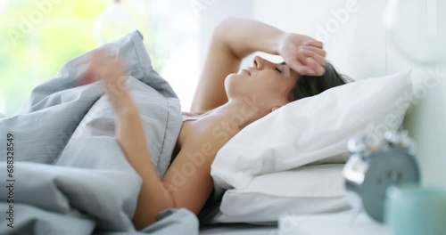Wake up, clock and sleeping woman with alarm in a bed for morning, alert or routine at home. Time, noise and female person in a bedroom with sound, watch or reaching for timer, stop or snooze photo