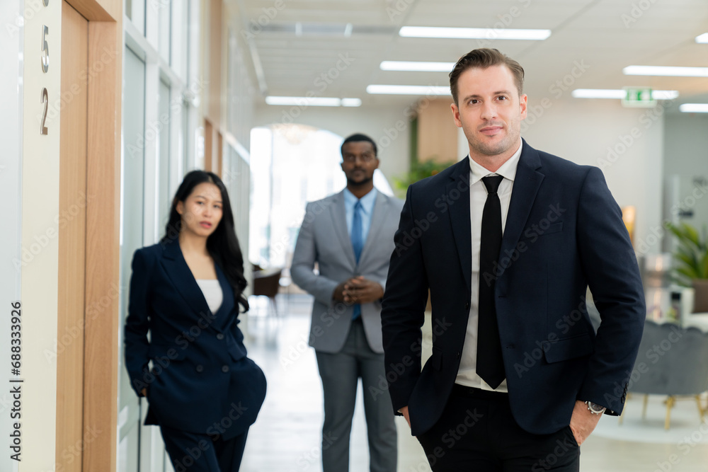 Professional businessman standing with arm folded while coworker stand behind. Group of diverse business people looking at camera with confident. Represent teamwork, working together. Ornamented.