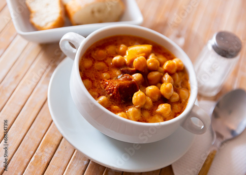 Portion of a traditional dish Spanish cuisine of Garbanzos a la riojana in a ceramic bowl. Served with bread photo