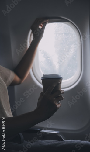 Asian woman enjoying enjoys a coffee comfortable flight while sitting in the airplane cabin  Passengers near the window.