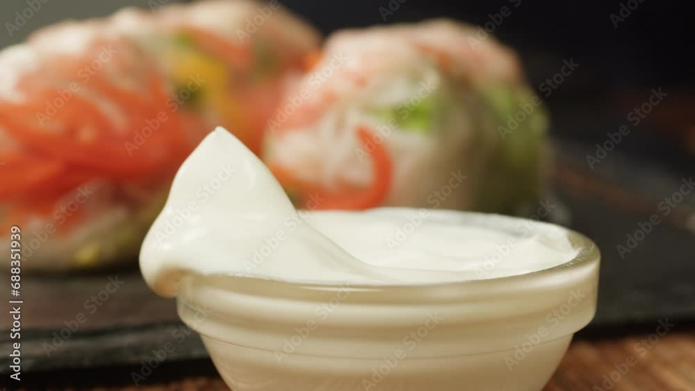 Dipping spring roll with shrimps and vegetables in white sauce close-up macro. Shrimp roll with rice papper. Cooking Fresh Vietnamese Spring Rolls. Healthy food.